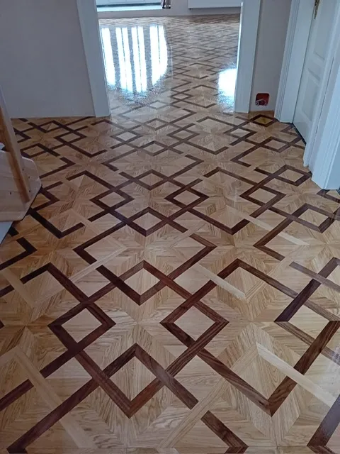 Lakované parkety ze světlého a tmavého dřeva skládané do geometrického vzoru